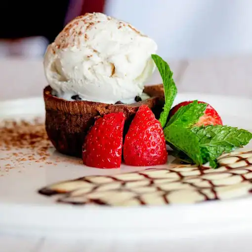 Decadent chocolate tartufo with vanilla ice cream and fresh strawberries on a white plate. Perfect for dessert lovers.