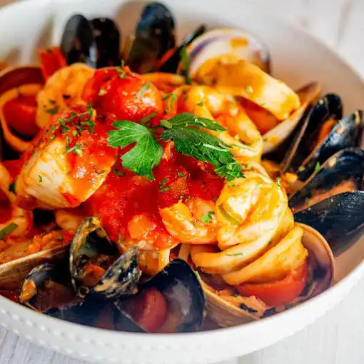 Delicious seafood pasta with fresh mussels, shrimp, and tomato sauce garnished with herbs.
