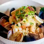 Delicious Truffle seafood risotto with fresh herbs, microgreens, and aromatic flavors in an elegant presentation.