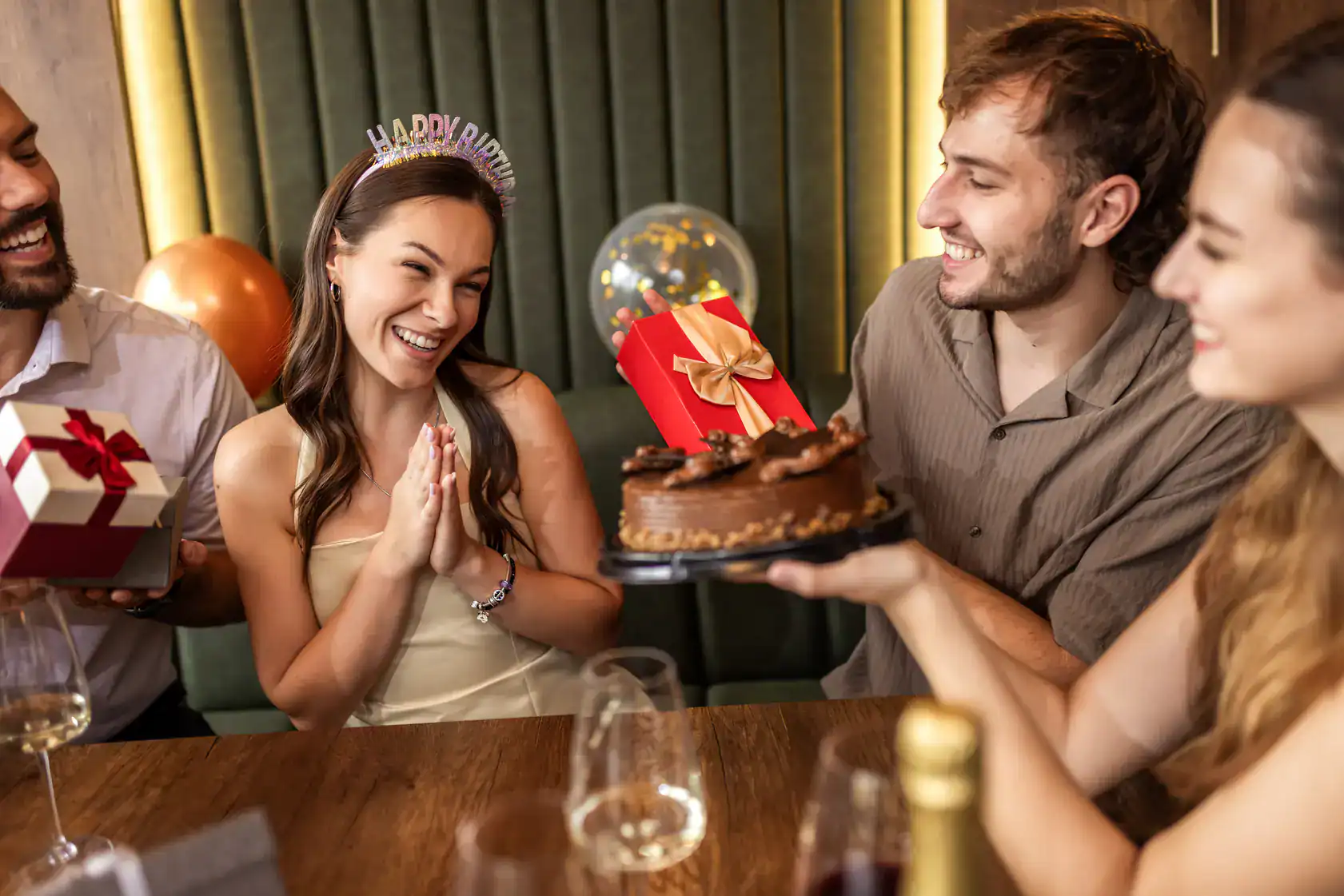 Happy birthday celebration with friends, cake, and presents at a lively party.