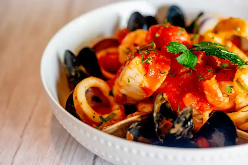 Delicious seafood pasta with fresh herbs, tomato sauce, and black mussels. Perfect for seafood lovers.